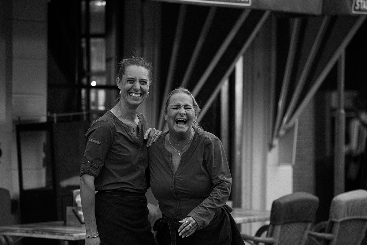 Twee medewerksters lachen samen op het terras