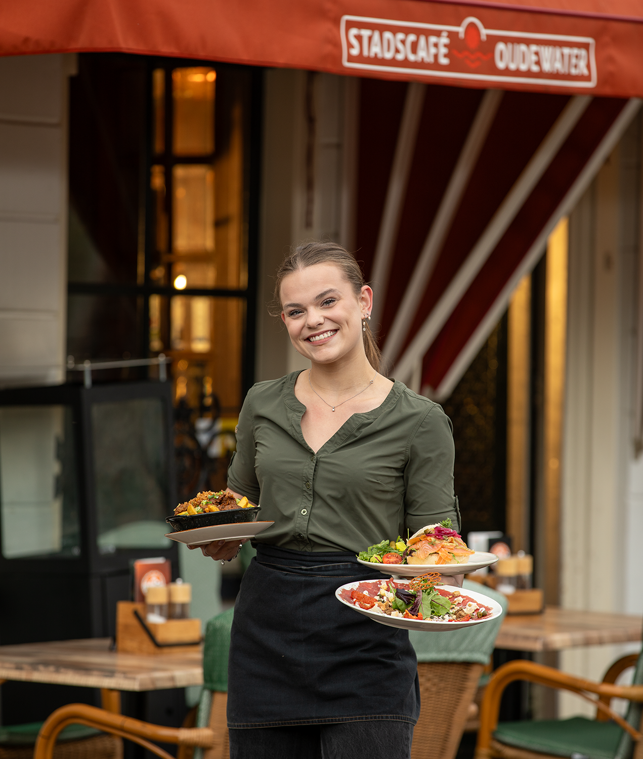 Medewerkster serveert drie gerechten onder de luifel van Stadscafé Oudewater