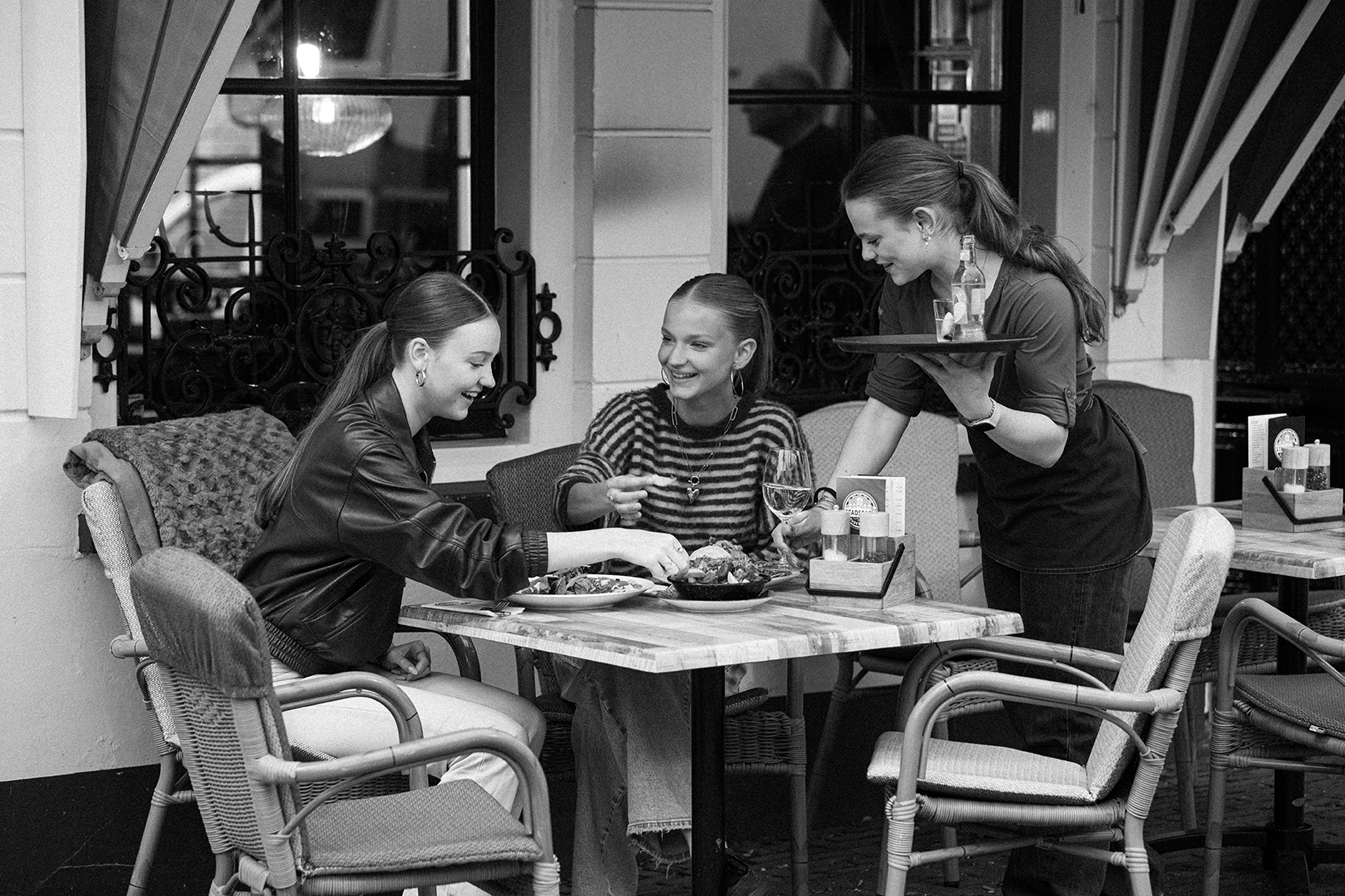 Medewerkster serveert gasten aan een tafel op het terras